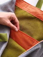 Interno della borsa grigia con tre tasche arancioni, foderaverde e dettagio bordo interno arancione