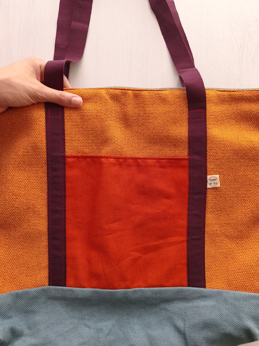 Borsa ocra con cinghie bordeaux, base della borsa grigio azzurro e tasca esterna arancione scuro