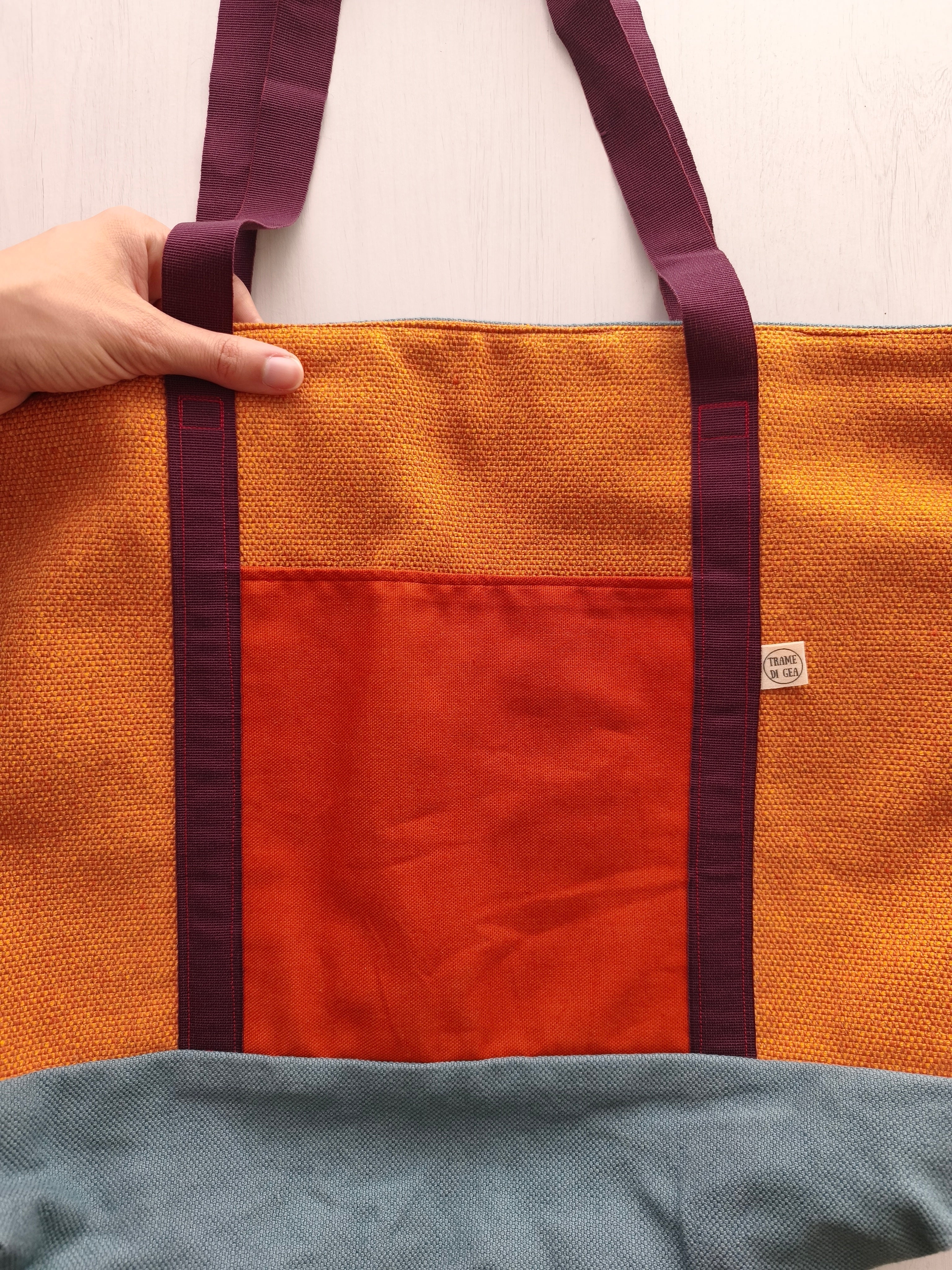 Borsa ocra con cinghie bordeaux, base della borsa grigio azzurro e tasca esterna arancione scuro