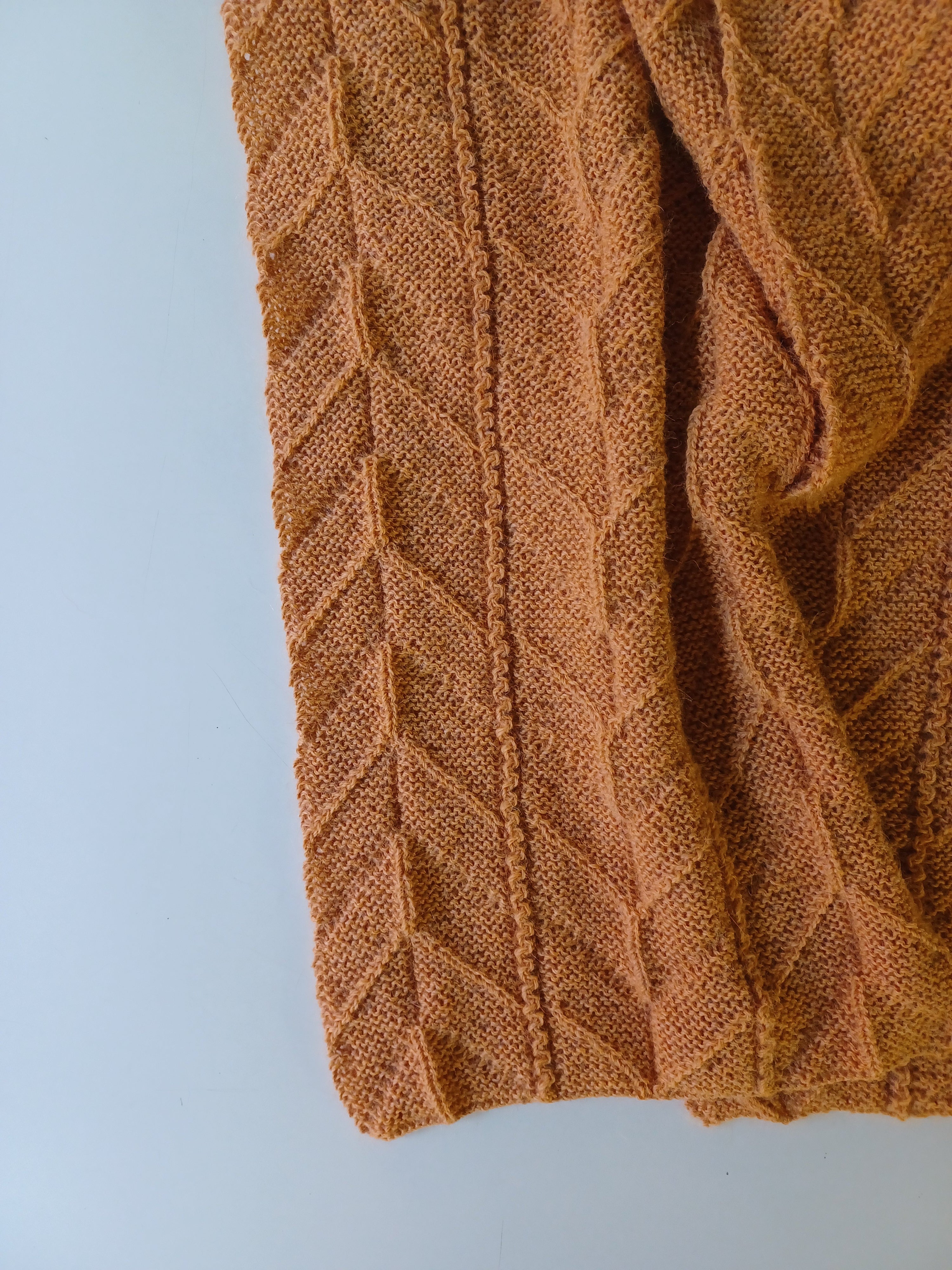 Sciarpa realizzata a maglia con filato di lana color senape con disegni geometrici ripetuti