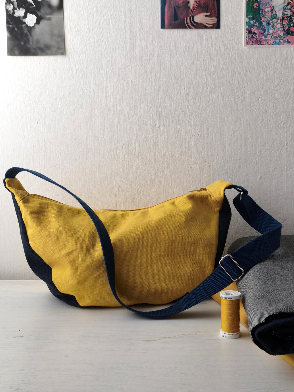 Moonbag appoggiata sul tavolo, gialla e denim scuro (blu) con tracolla blu scuro
