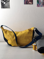 Moonbag appoggiata sul tavolo, gialla e denim scuro (blu) con tracolla blu scuro