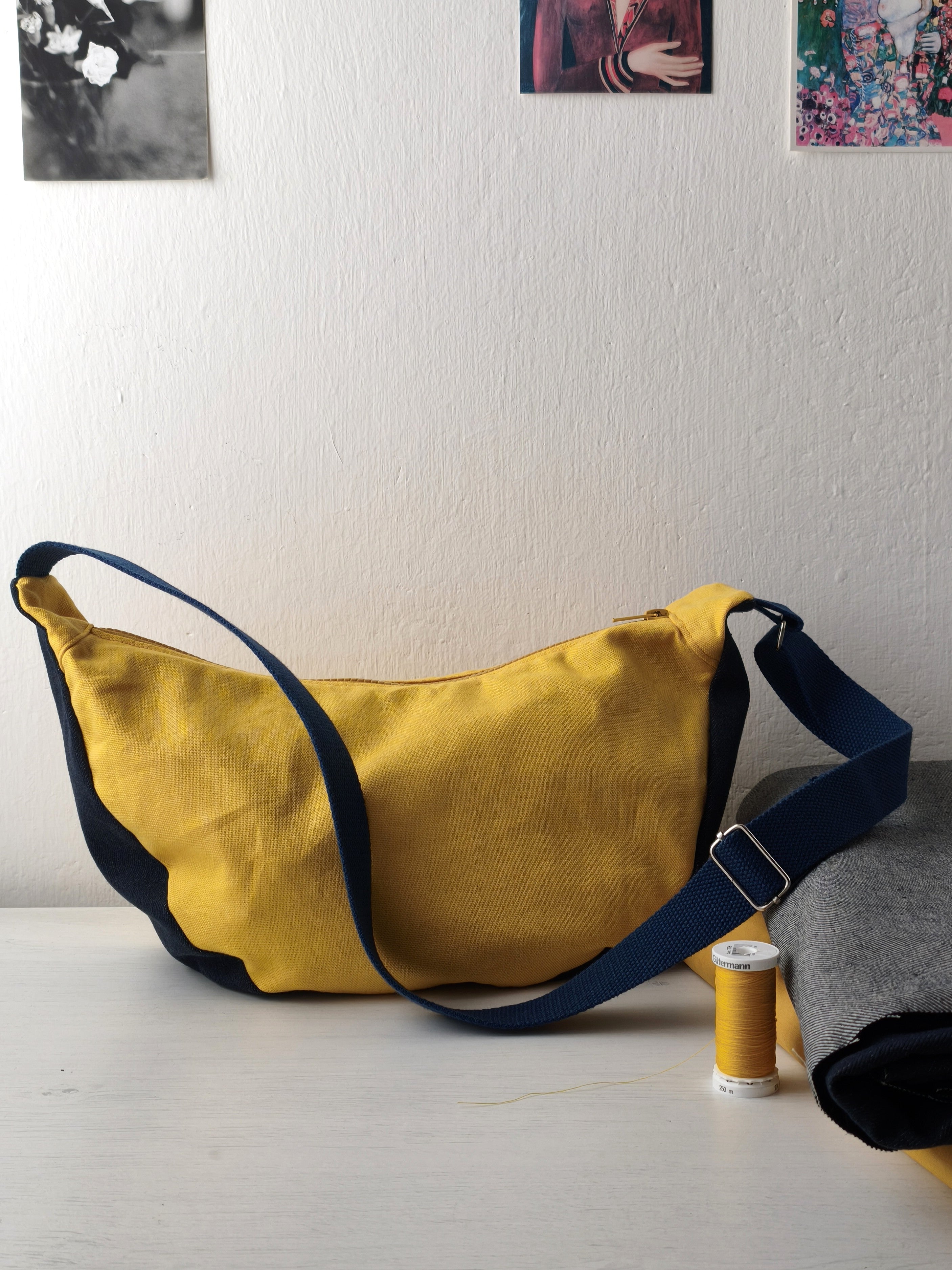 Moonbag appoggiata sul tavolo, gialla e denim scuro (blu) con tracolla blu scuro
