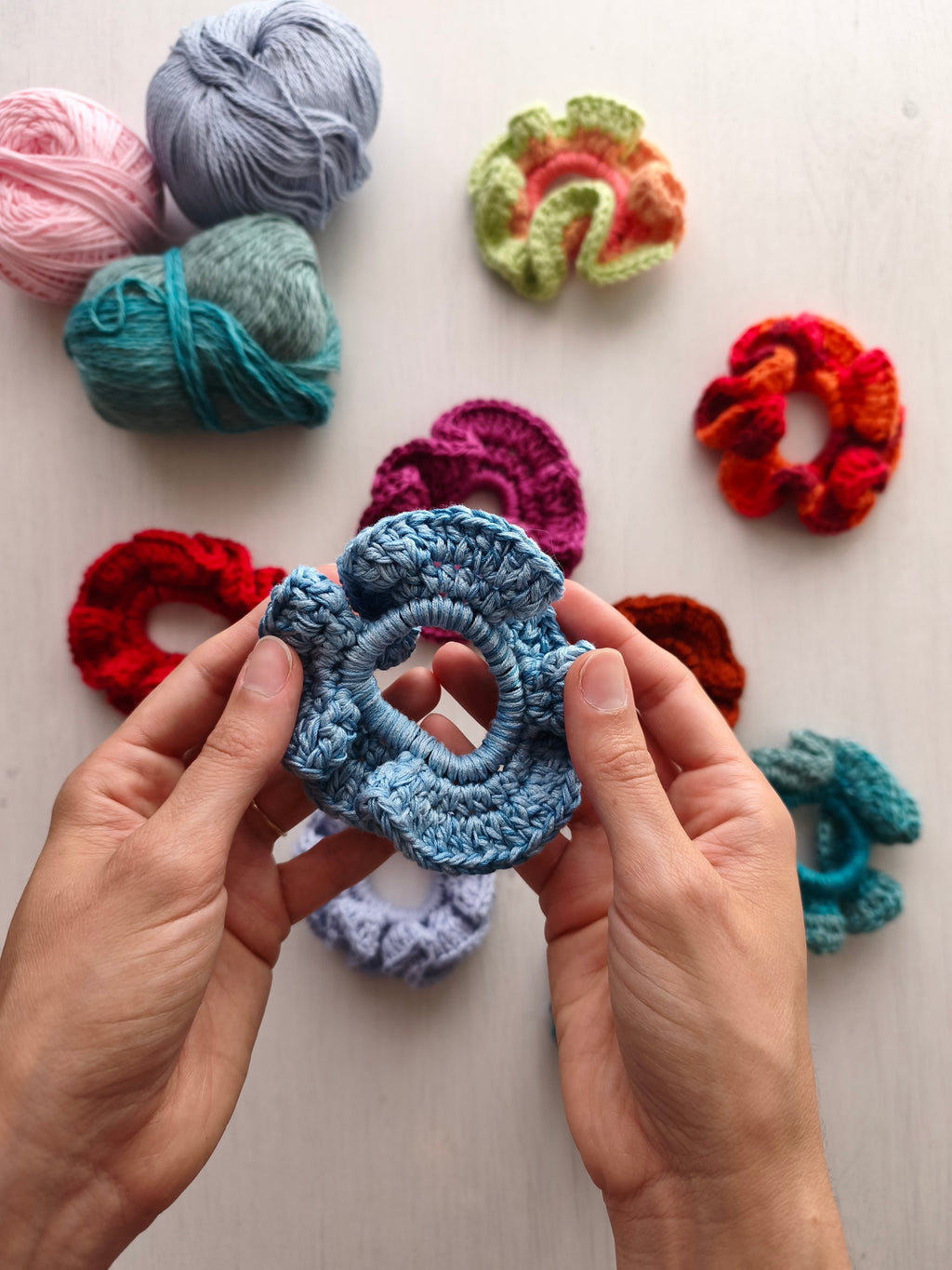 Mani che tengono uno scrunchie all'uncinetto azzurro