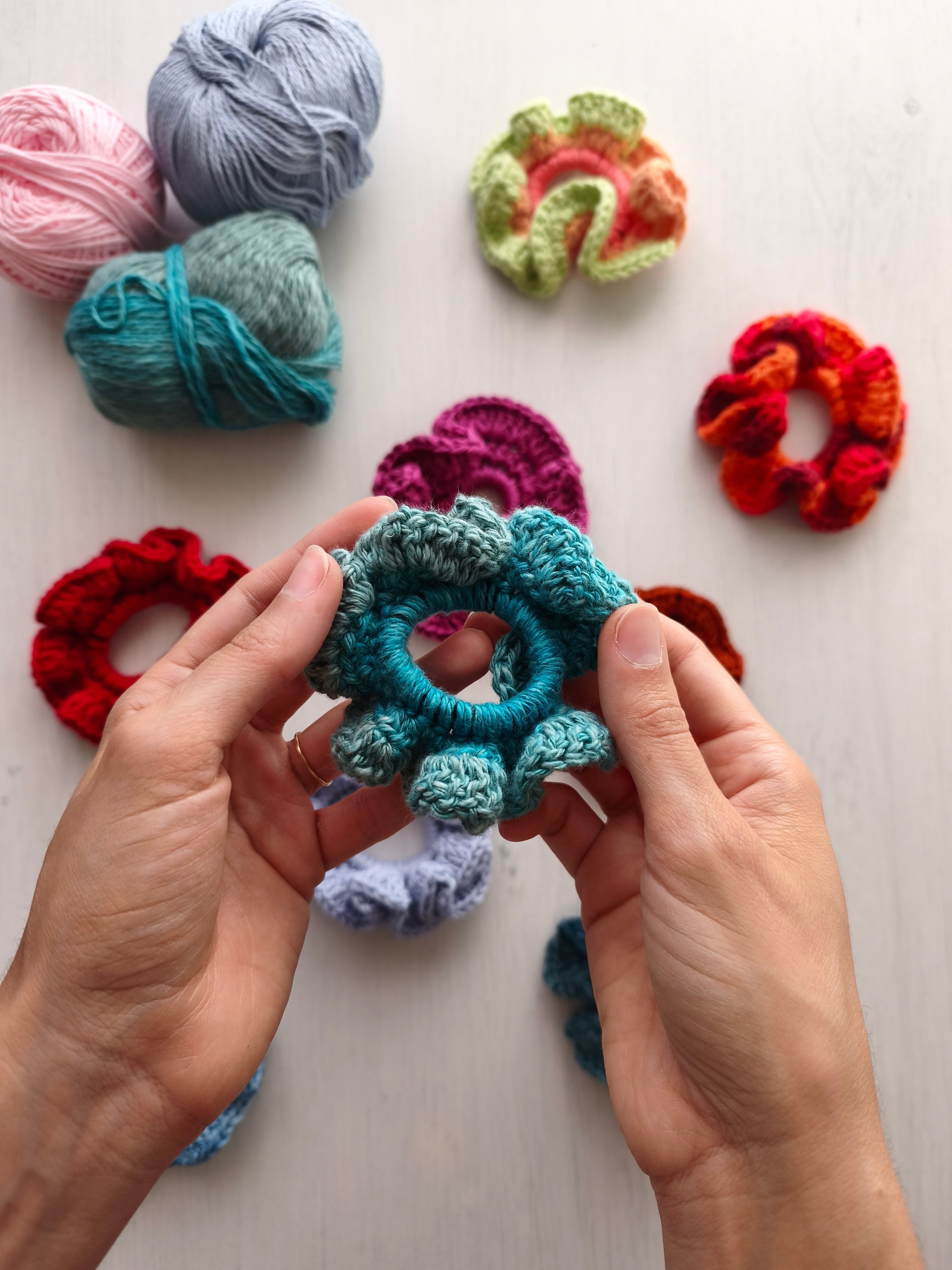 Mani che tengono uno scrunchie all'uncinetto azzurro in canapa