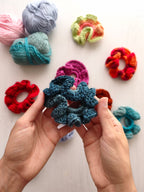 Mani che tengono uno scrunchie all'uncinetto blu