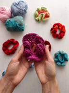 Mani che tengono uno scrunchie all'uncinetto fuxia