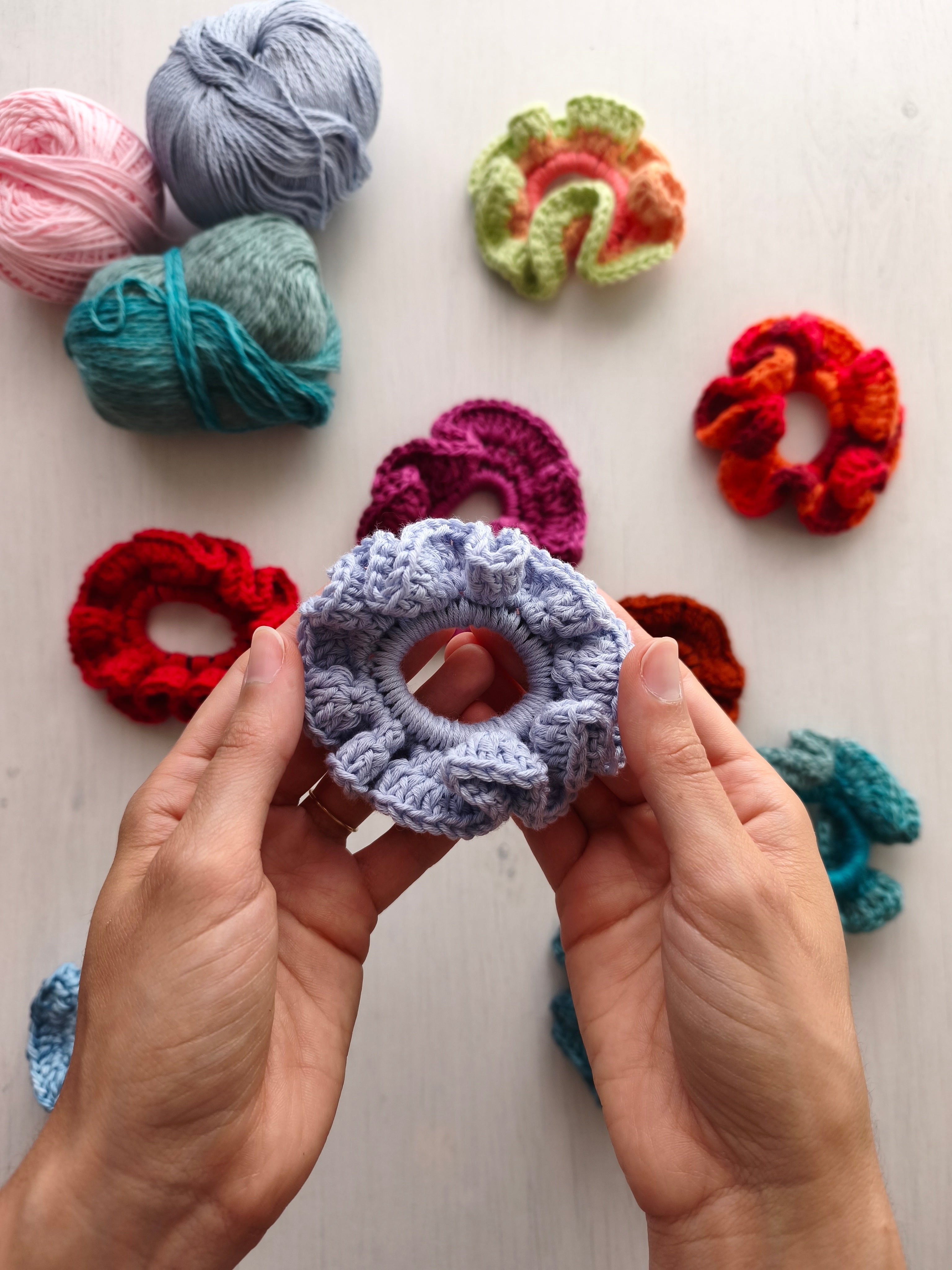 Mani che tengono uno scrunchie all'uncinetto lilla