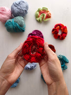 Mani che tengono uno scrunchie all'uncinetto rosso