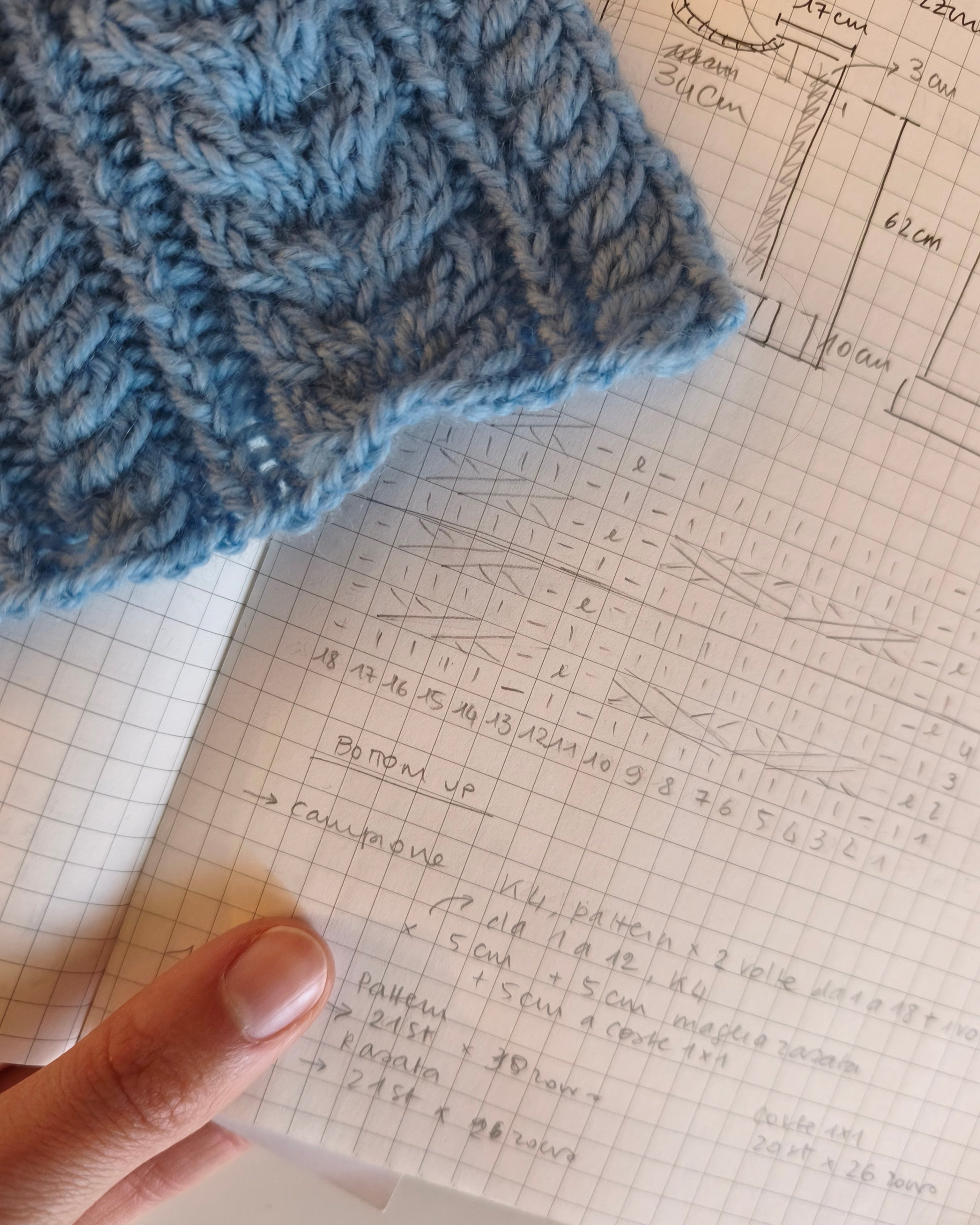 quaderno su cui sono stati scritti i calcoli per la realizzazione di un capo su misura con accanto un campione di lavorazione a maglia